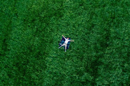 Téléchargez les photos : Un homme amoureux sur une grande prairie verte dans le parc. Vue de drone du bonheur et de la sérénité. - en image libre de droit