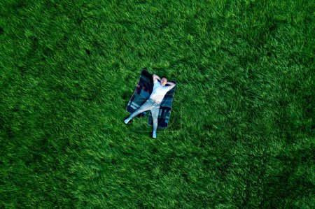 Téléchargez les photos : Un homme amoureux sur une grande prairie verte dans le parc. Vue de drone du bonheur et de la sérénité. - en image libre de droit