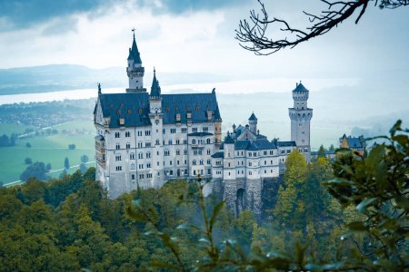 Téléchargez les photos : Vue du château de Neuschwanstein par un jour d'automne pluvieux. Pistes montagneuses et rochers couverts de forêt dans les environs du château. - en image libre de droit