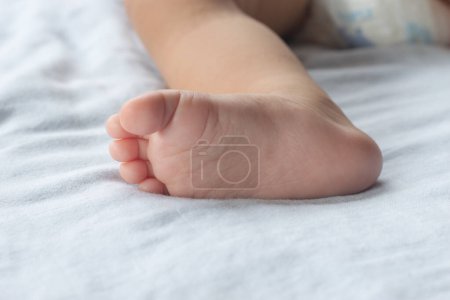 Gros plan des pieds doux du bébé sur le matelas.
