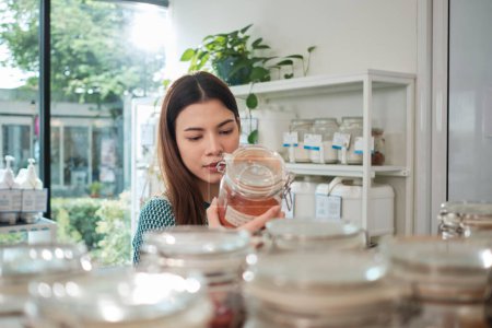 Photo for Young White female customer is choosing and shopping for organic products in glass jars at refill store, zero-waste grocery, and plastic-free, and environment-friendly retail, sustainable lifestyles. - Royalty Free Image