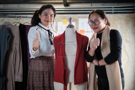 Téléchargez les photos : Fashion team people, Asian female designer and teen assistant in studio, thumb up and smile, happy working with thread and sewing for dress design, professional boutique tailor SME entrepreneur. - en image libre de droit