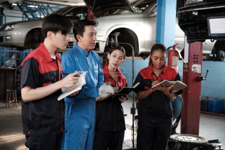 Specialist lecture. Male supervisor engineer describe automotive suspension fixing with mechanic worker staff teams for repair work at car service garage and maintenance jobs in automobile industry.