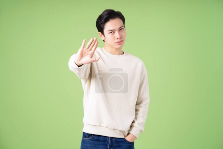 Téléchargez les photos : Portrait de jeune homme asiatique posant sur fond vert - en image libre de droit