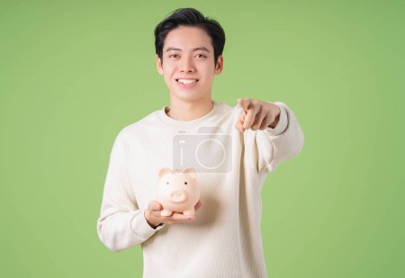 Foto de Imagen de un joven asiático sosteniendo alcancía en el fondo - Imagen libre de derechos