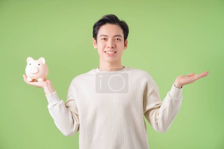Foto de Imagen de un joven asiático sosteniendo alcancía en el fondo - Imagen libre de derechos