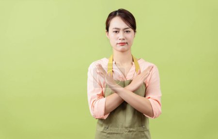 Photo of young Asian female housekeeper on green background