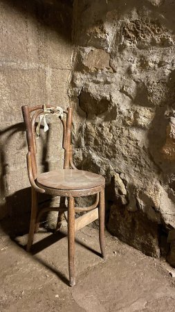 Foto de Una vieja y sucia silla de madera en un rincón de una vieja casa de piedra - Imagen libre de derechos