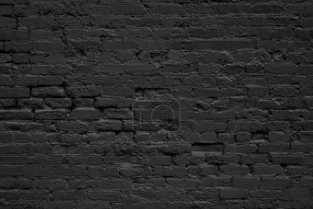 Gros plan de mur de briques grunge peint en noir.