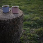a cup of coffee stands on a wooden table in the garden