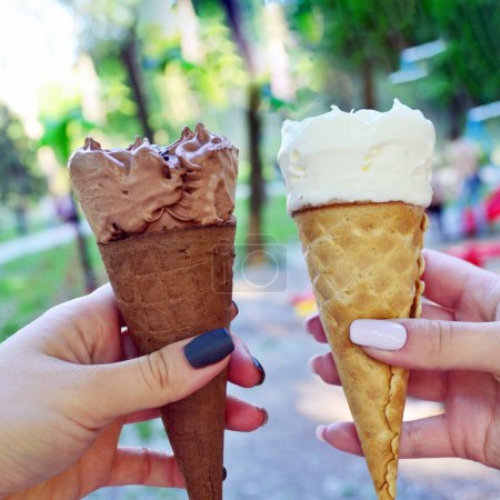 Téléchargez les photos : Mains tenant de la crème glacée dans un cône de gaufre - en image libre de droit