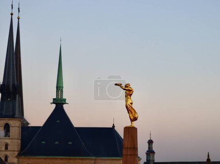 Foto de Golden Lady o Gelle Fra Monumento al Recuerdo y torres de aguja y campanario de la catedral gótica de Notre-Dame. Luxemburgo, Luxemburgo - 17 de diciembre de 2022 - Imagen libre de derechos
