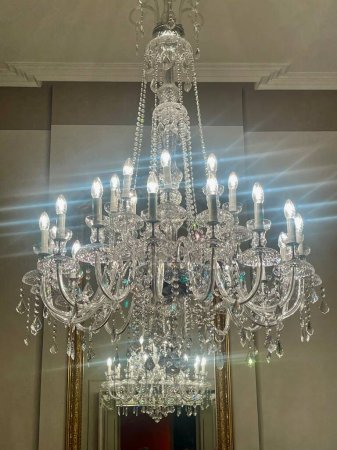Téléchargez les photos : Splendid candelabra with multiple branches reflecting in gold framed mirror, interior detail in luxurious historic hall, electric light bulbs in shape of candles, crystal abat jours and drop hangers - en image libre de droit