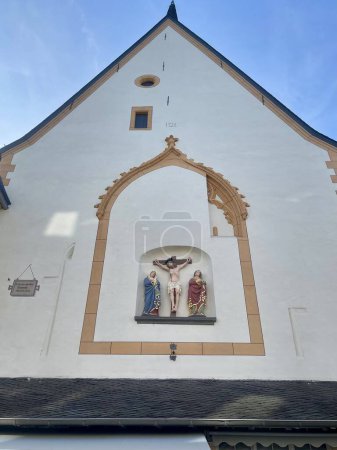 Mittelalterliches Kruzifix an der Fassade der Kirche St. Gangolf in Trier. Jesus am Kreuz und trauernde Mutter Maria und der heilige Johannes