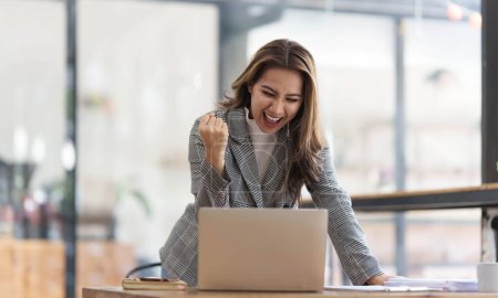 Téléchargez les photos : Pretty Asian businesswoman sitting on a laptop And the work came out successfully and the goal was achieved, happy and satisfied with her... - en image libre de droit