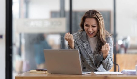 Téléchargez les photos : Pretty Asian businesswoman sitting on a laptop And the work came out successfully and the goal was achieved, happy and satisfied with her... - en image libre de droit