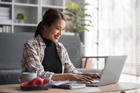 Beautiful and inspired Asian woman working on her tasks on laptop in a living room on the weekend... Mouse Pad 654605362