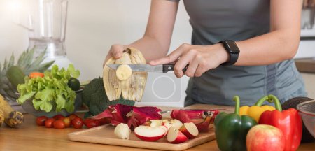 Foto de Mujer asiática sana cuida su salud comiendo ensalada de verduras y frutas, añadiendo vitaminas en la cocina.. - Imagen libre de derechos