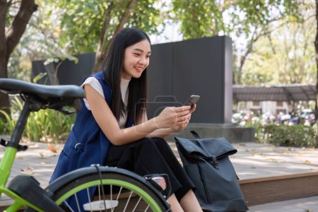 Asiatische Geschäftsfrau fährt mit dem Fahrrad in die Stadt, um außerhalb der Stadt zu arbeiten, um die Kohlendioxidemissionen zu reduzieren. Alternative Transportmittel für grüne Energie.
