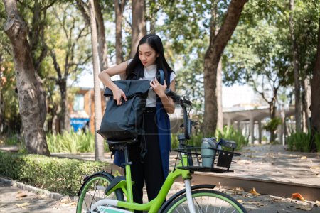 Foto de Empresaria asiática monta una bicicleta en la ciudad para trabajar fuera de la ciudad para reducir las emisiones de carbono. Transporte alternativo para la energía verde. - Imagen libre de derechos