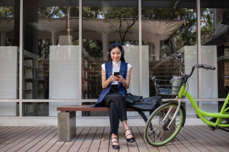 Foto de Empresaria asiática monta una bicicleta en la ciudad para trabajar fuera de la ciudad para reducir las emisiones de carbono. Transporte alternativo para la energía verde. - Imagen libre de derechos