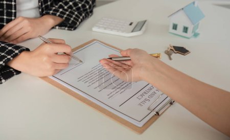 Vertreter des Immobilienprojekts und Kunde unterzeichnen Dokumente Hauskaufvertrag Buch.