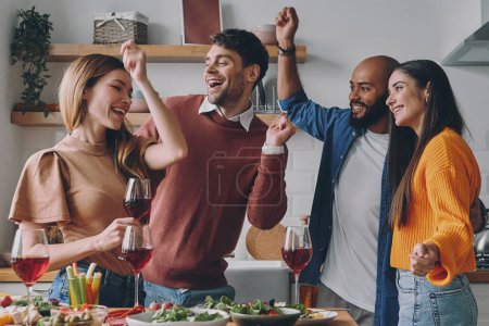 Photo for Cheerful young people dancing and smiling while enjoying party at home together - Royalty Free Image