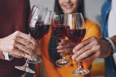 Photo for Close-up of young people toasting with wine while spending time together - Royalty Free Image