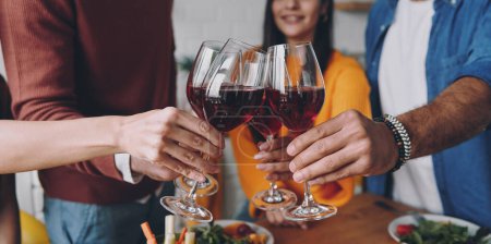 Téléchargez les photos : Gros plan de jeunes qui trinquent avec du vin tout en dînant ensemble à la maison - en image libre de droit