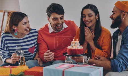 Téléchargez les photos : Jeunes gens heureux félicitant ami avec anniversaire tout en célébrant ensemble à la maison - en image libre de droit