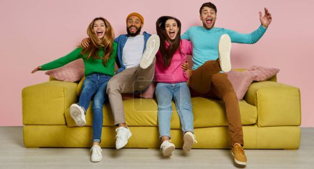 Téléchargez les photos : Plan studio de jeunes gens heureux embrassant et sautant sur le canapé ensemble - en image libre de droit