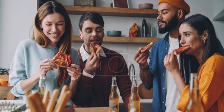 Photo for Cheerful young people eating pizza and smiling while enjoying fun time together - Royalty Free Image