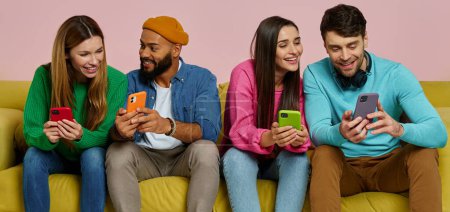 Photo for Studio shot of young people using smart phones and communicating while sitting on couch together - Royalty Free Image