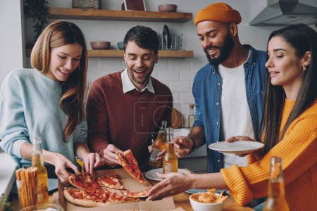 Téléchargez les photos : Groupe de jeunes gens heureux mangeant de la pizza tout en profitant du plaisir ensemble - en image libre de droit