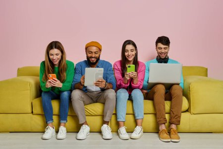 Photo for Studio shot of young people using technologies and smiling while sitting on the couch together - Royalty Free Image