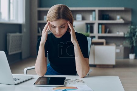 Téléchargez les photos : Femme d'affaires frustrée touchant la tête et gardant les yeux fermés pendant qu'elle est assise dans le bureau - en image libre de droit