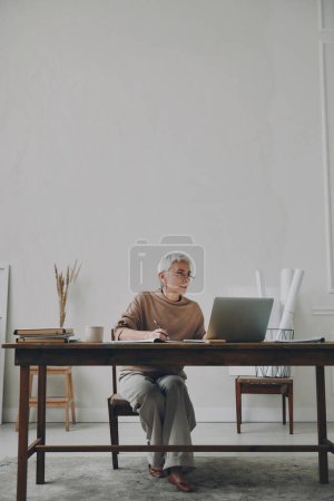 Photo for Confident senior businesswoman using laptop while sitting at her working place - Royalty Free Image