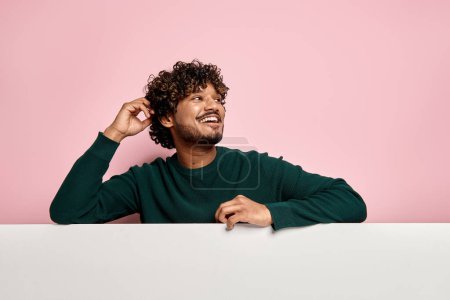 Photo for Happy young Indian man leaning at the copy space and smiling against pink background - Royalty Free Image