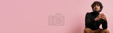 Téléchargez les photos : Élégant homme indien regardant l'espace de copie tout en étant assis sur fond rose - en image libre de droit