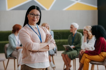 Téléchargez les photos : Femme asiatique confiante regardant la caméra tout en visitant classe de formation de groupe pour les femmes - en image libre de droit