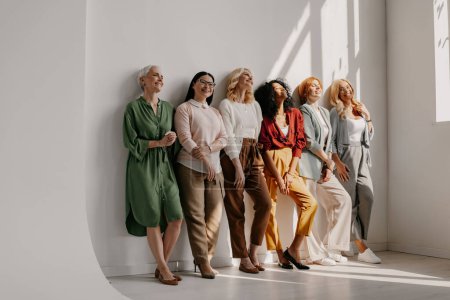 Photo for Multi-ethnic group of mature women bonding and smiling while leaning on the wall together - Royalty Free Image