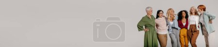 Téléchargez les photos : Groupe multi-ethnique de femmes mûres confiantes embrassant et souriant sur fond gris - en image libre de droit