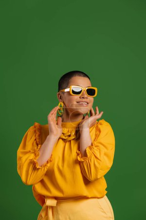 Foto de Moda joven mujer de pelo corto en gafas de moda sonriendo contra el fondo verde - Imagen libre de derechos