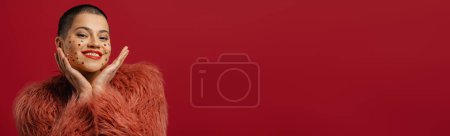 Foto de Feliz joven mujer de pelo corto con cristales brillantes sobre su cara gestos contra el fondo rojo - Imagen libre de derechos