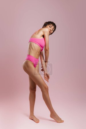 Foto de Longitud completa de la joven mujer de pelo corto en ropa interior de pie sobre fondo de color - Imagen libre de derechos