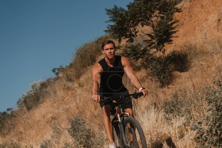 Téléchargez les photos : Jeune homme athlétique en vêtements de sport équitation vélo par montagne en plein air - en image libre de droit