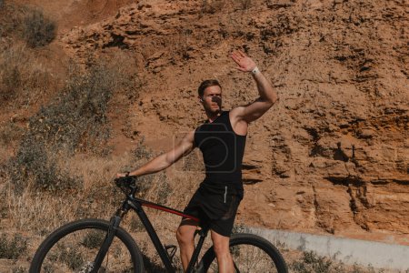 Téléchargez les photos : Jeune homme sportif couvrant le visage de la lumière du soleil tout en faisant du vélo à l'extérieur - en image libre de droit