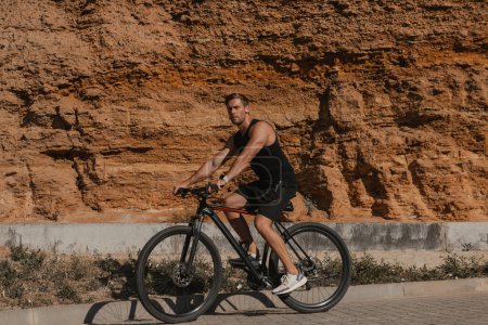 Téléchargez les photos : Jeune homme confiant en vêtements de sport à vélo contre les montagnes rocheuses à l'extérieur - en image libre de droit