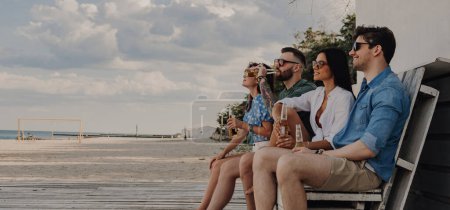 Foto de Grupo de amigos gozosos disfrutando de la vista al mar mientras pasan tiempo juntos cerca de la casa de la playa - Imagen libre de derechos