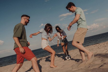 Téléchargez les photos : Groupe de jeunes gens heureux passer du temps amusant tout en jouant au football sur la plage ensemble - en image libre de droit